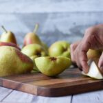 Буркани с домашен компот от круши, подредени на дървена маса