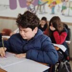 Ученик се подготвя за изпит с учебници на масата