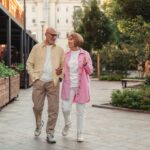 Възрастна двойка се разхожда в парка сред есенни листа
