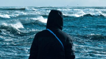 Жена гледа през прозорец към облачно небе, символизираща промяна в настроението при смяна на времето
