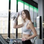 Жена тренира бягане на пътека във фитнес зала