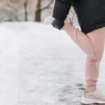 Жена се загрява преди тренировка на открито през студен ден