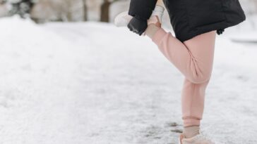 Жена се загрява преди тренировка на открито през студен ден